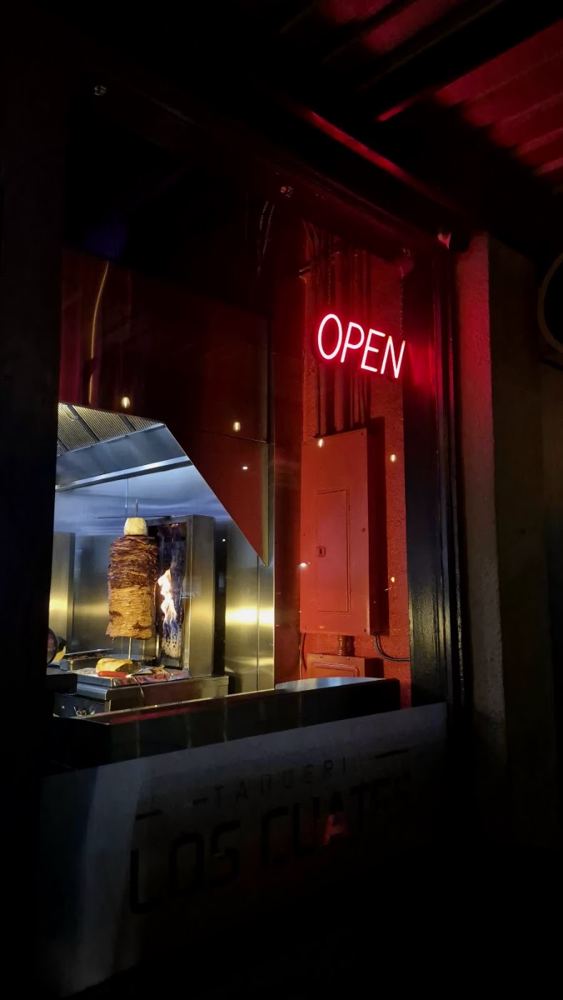 Taqueria Los Cuates at night with the open sign lit